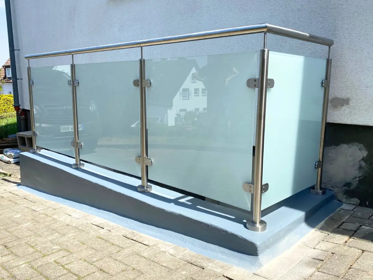 Glasgeländer mit Edelstahlpfosten vor einem Wohnhaus